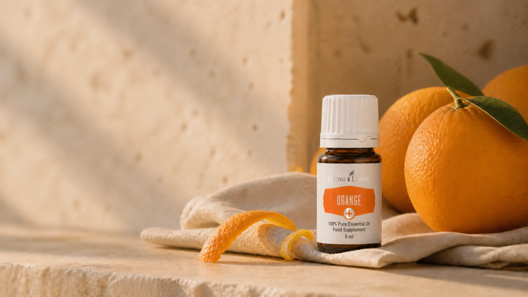 Young Living Orange+ 5 ml Flasche mit Orangen und Schale in warmem Nachmittagslicht